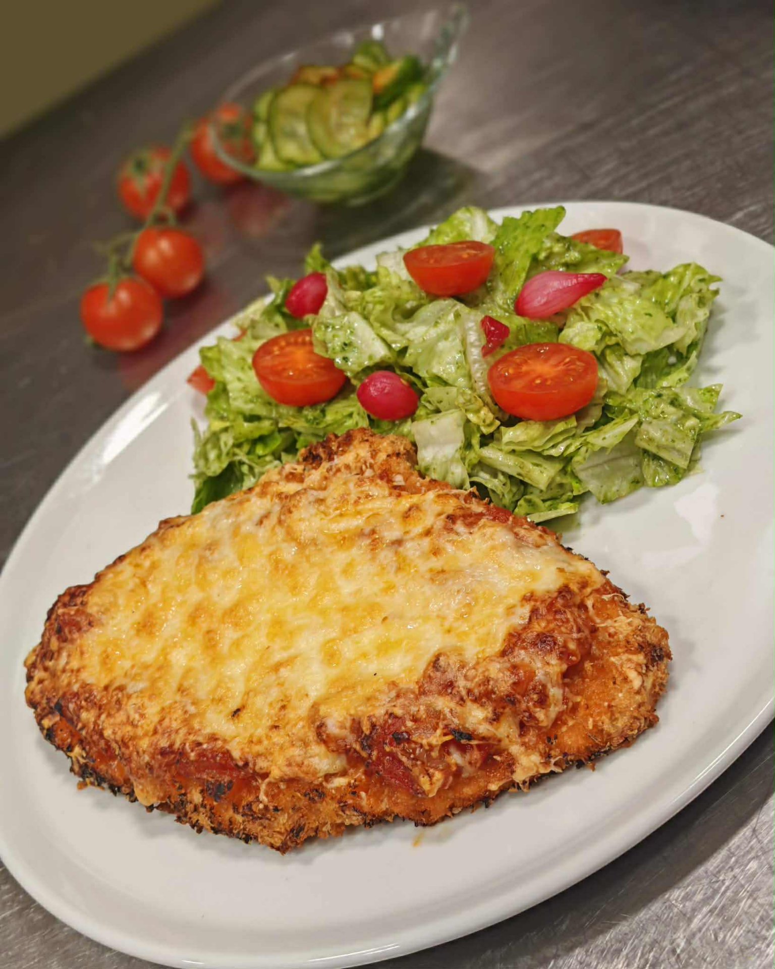 Pankó morzsában bundázott sertéskaraj pecorino-s sajttal és paradicsommal besütve, fokhagymás-bazsalikomolajos salátával